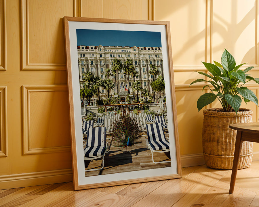 Framed photograph of a beach scene with striped chairs against a yellow wall.