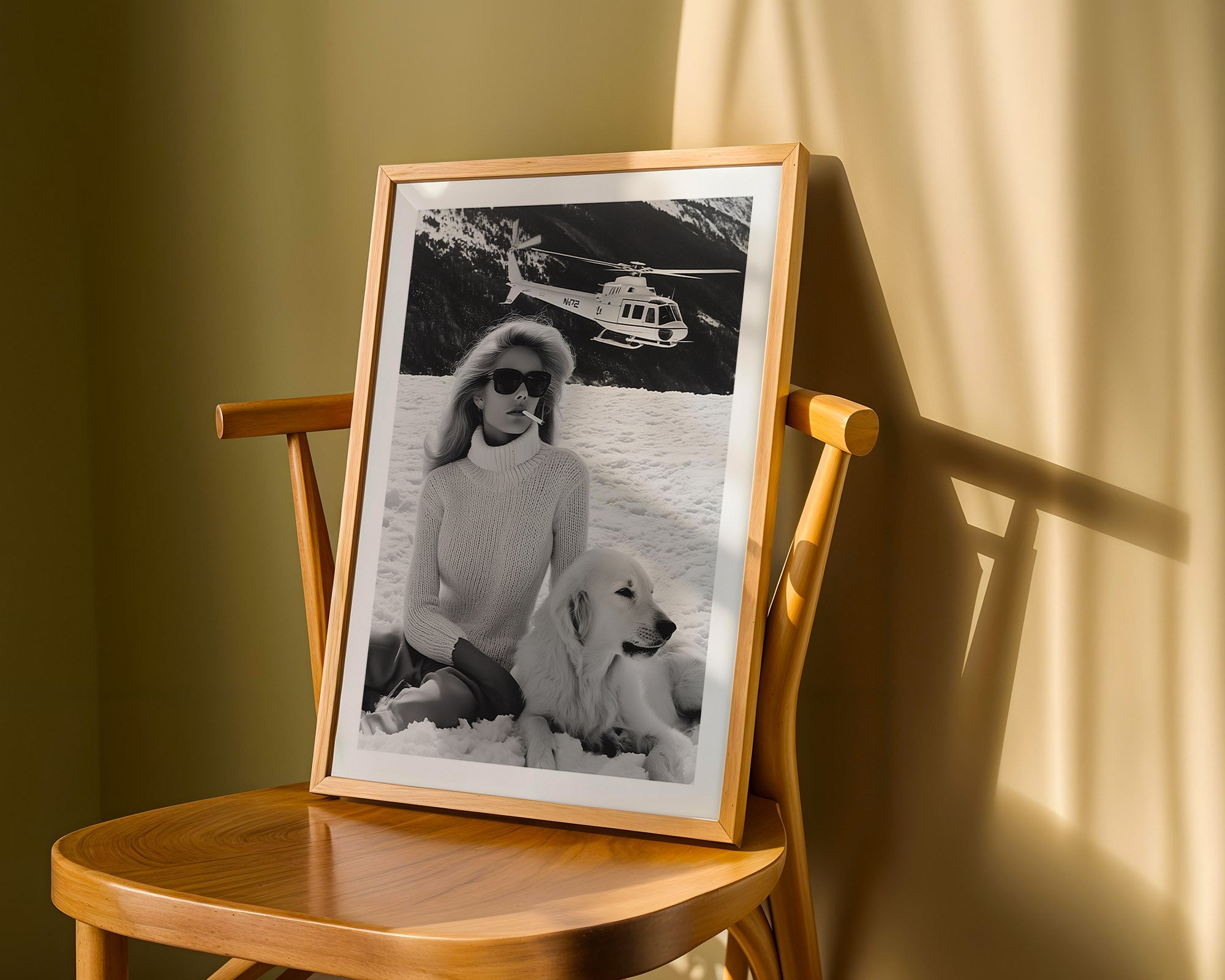 Framed black and white photo of a woman with a dog on a wooden chair against a green wall.