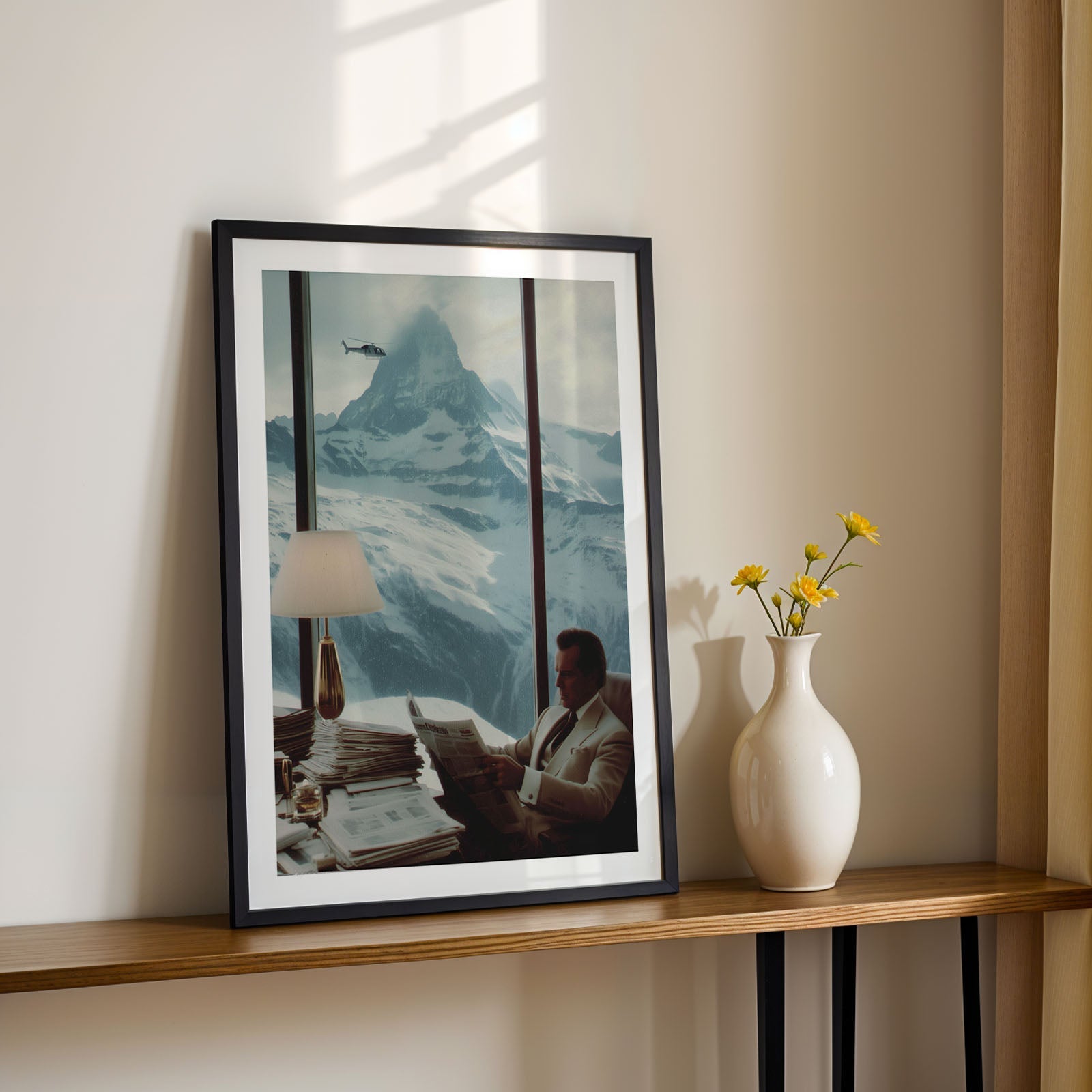 Framed artwork on a shelf with a vase and flowers in a room with sunlight streaming in.