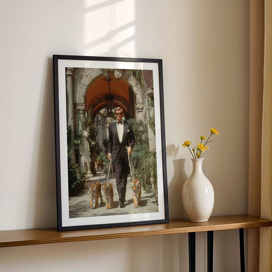 Framed photograph of a man in a suit with two tiger cubs on a shelf next to a vase with flowers.