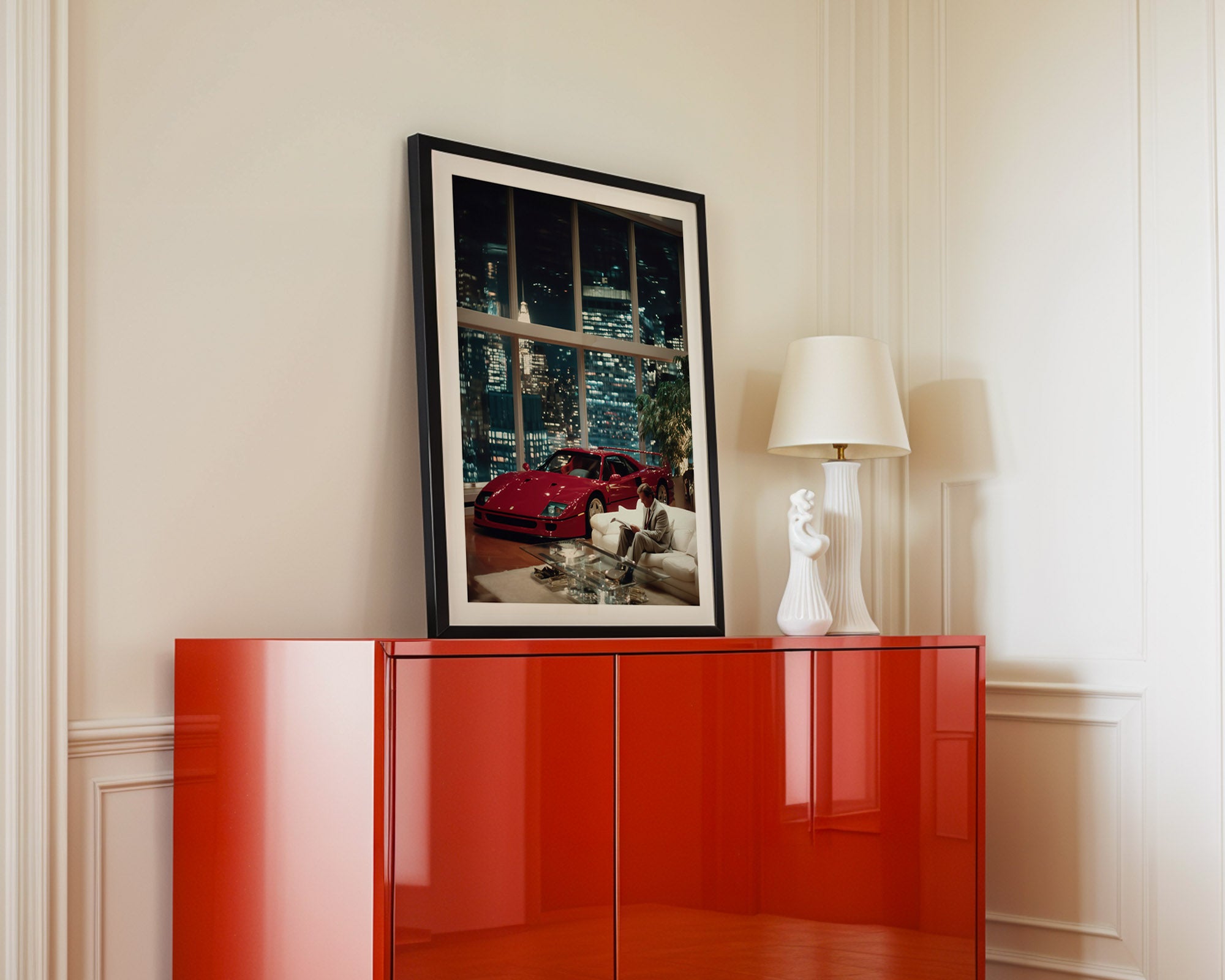 Red cabinet with a framed picture of a red Ferrari on a white wall.