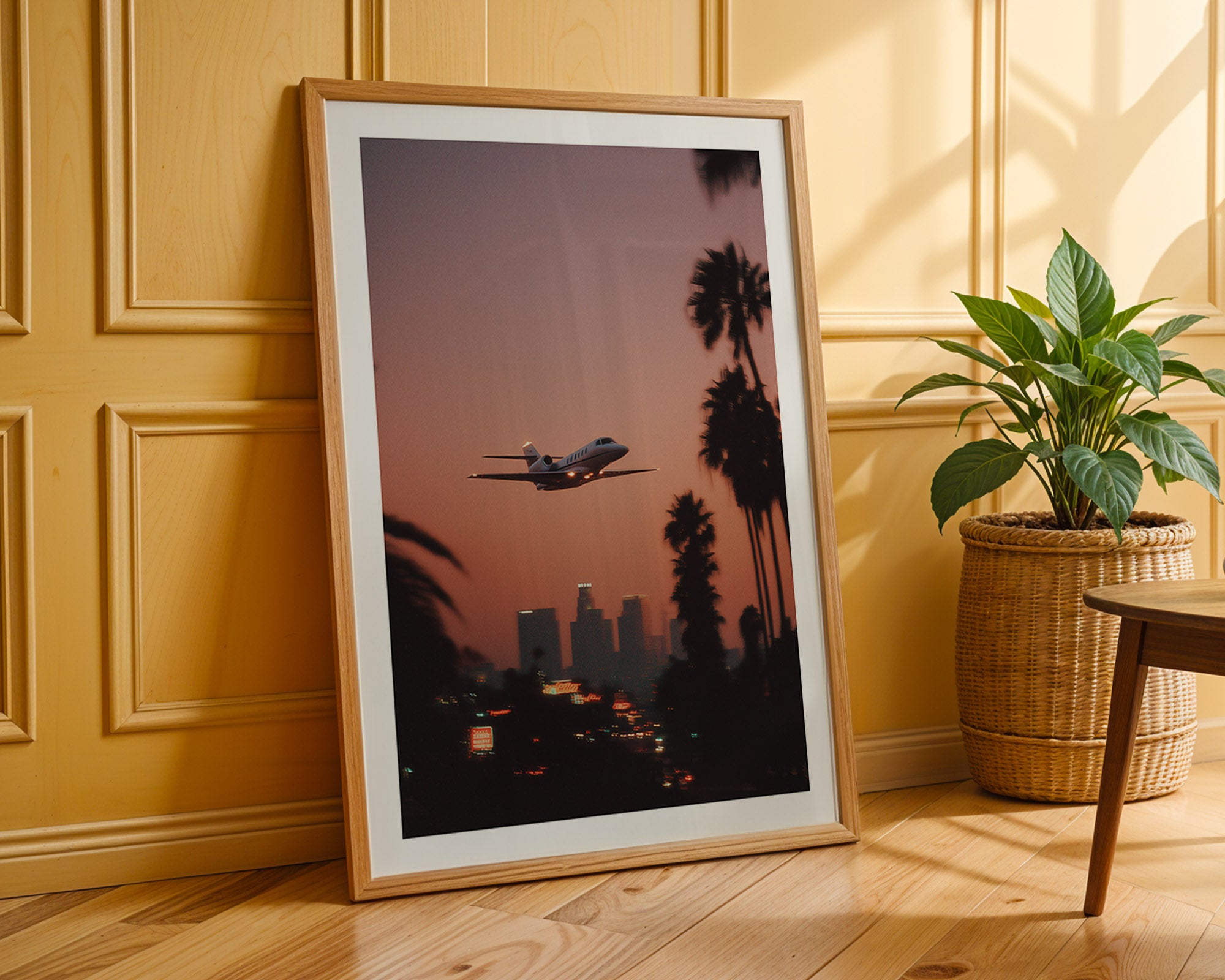 Framed artwork of an airplane flying over palm trees and city skyline on a wooden floor.