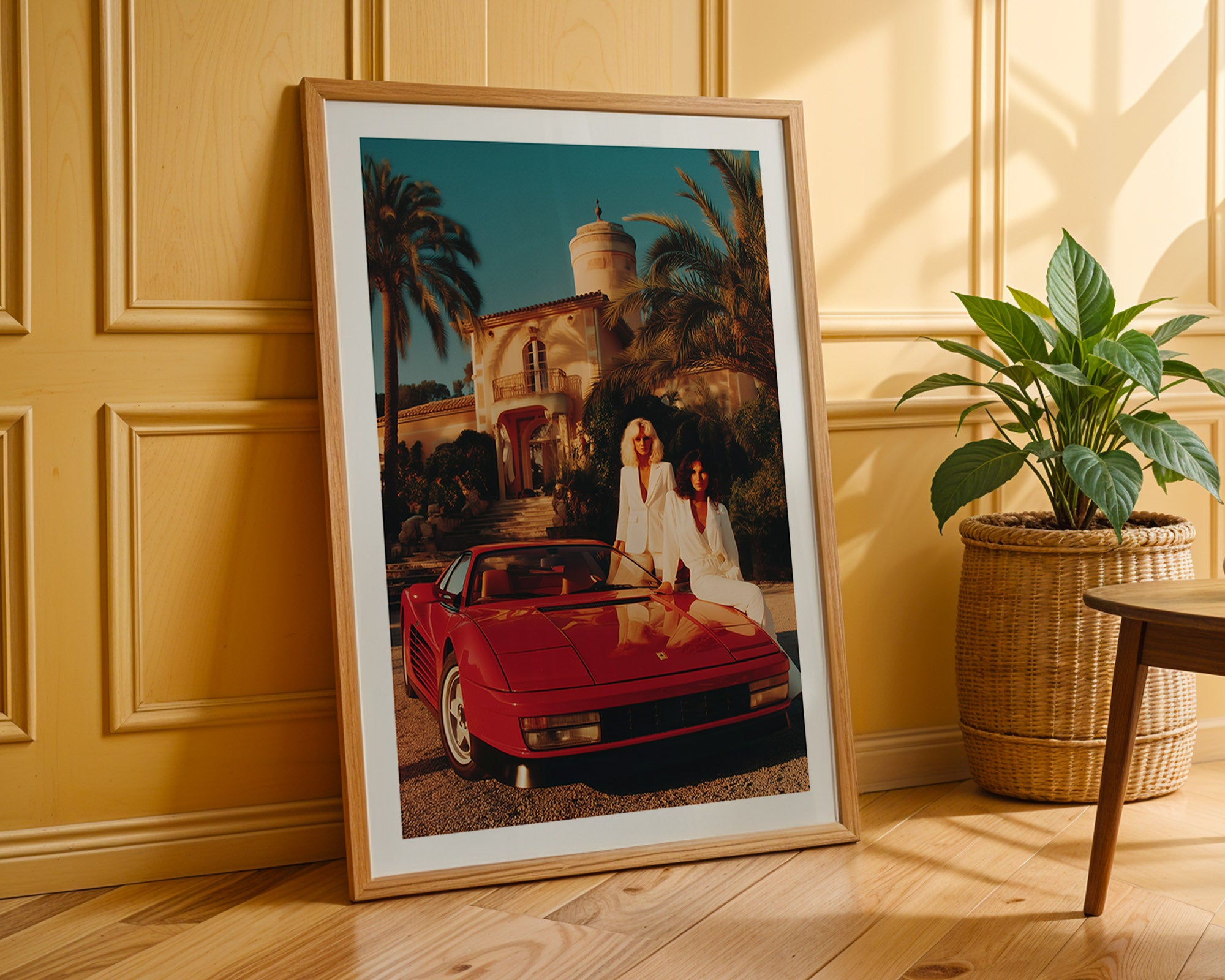 Framed photograph of a couple in a red Ferrari against a palm tree backdrop, placed on a wooden floor.