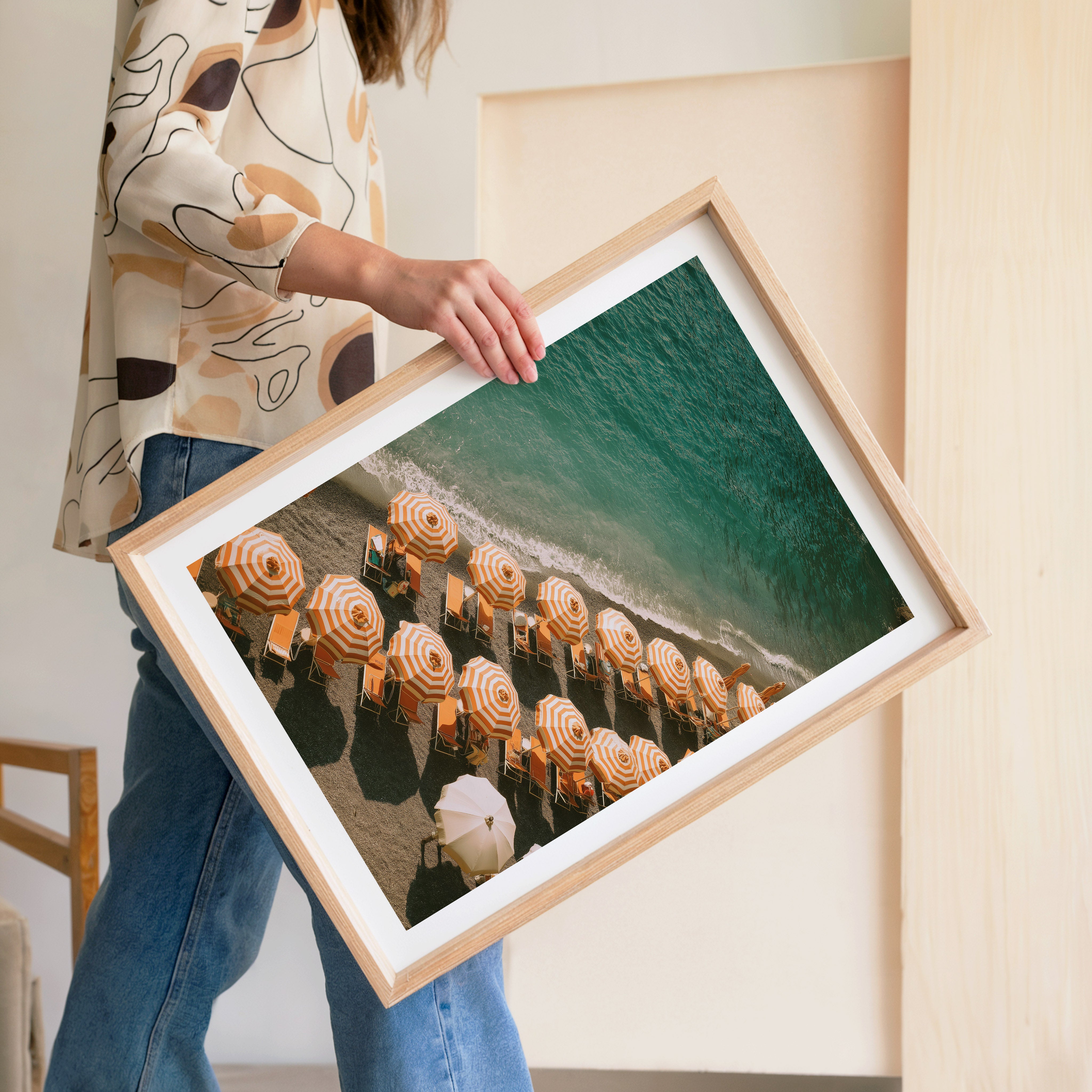 Person holding a framed photograph of beach umbrellas by the ocean