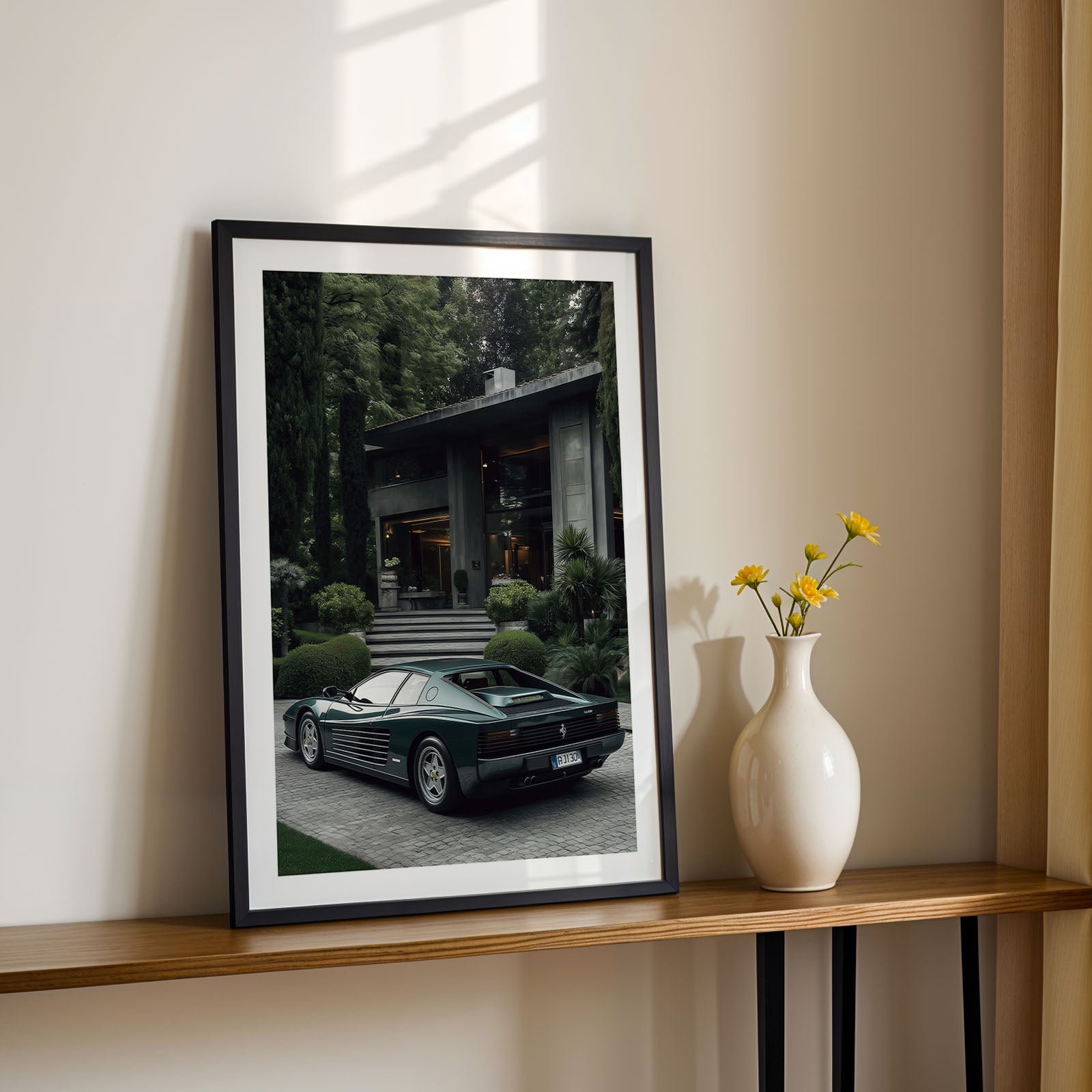 Framed photograph of a Ferrari Testarossa on a shelf with a vase and flowers in the background