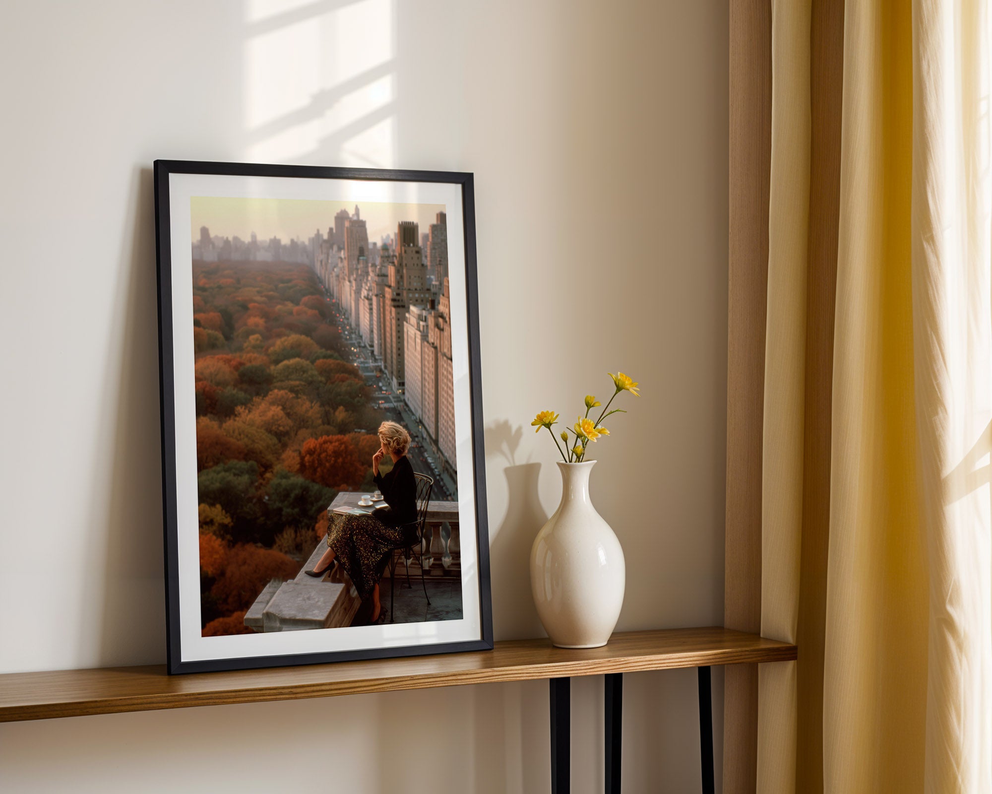 Framed artwork on a shelf with a vase of flowers next to it.
