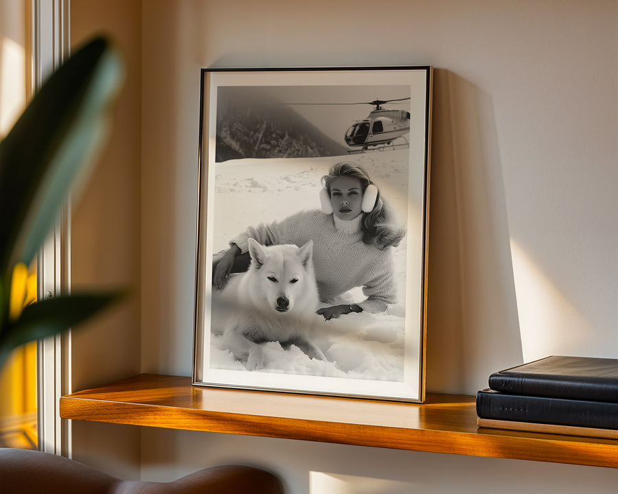 Framed black and white photo of a woman with a dog on a snowy landscape, displayed on a wooden shelf.