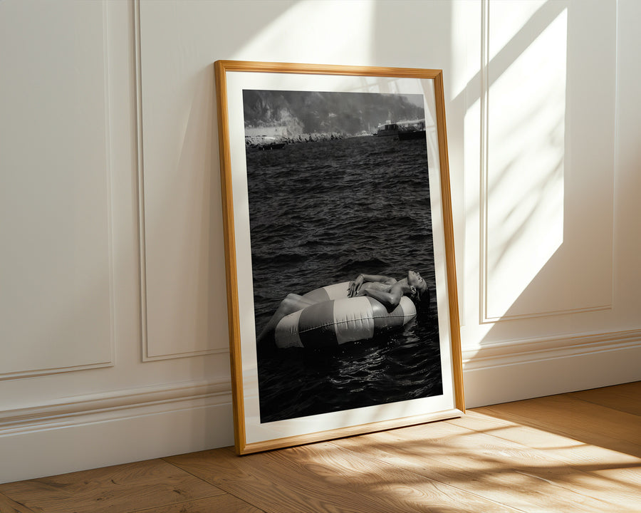 Framed black and white photograph of a striped boat on water leaning against a wall.