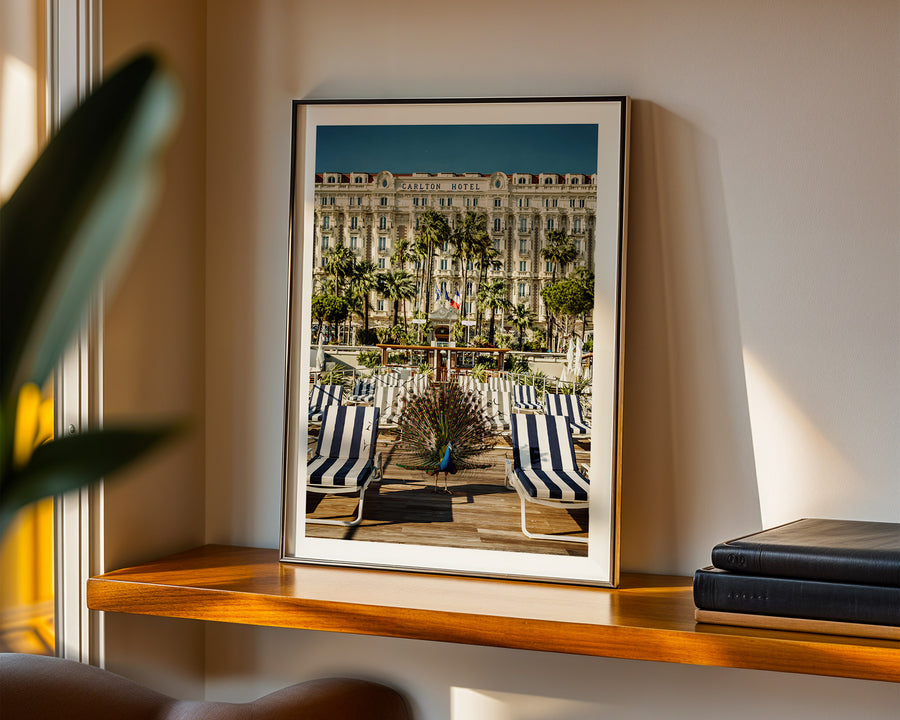 Framed photograph of a beach scene with lounge chairs on a shelf.