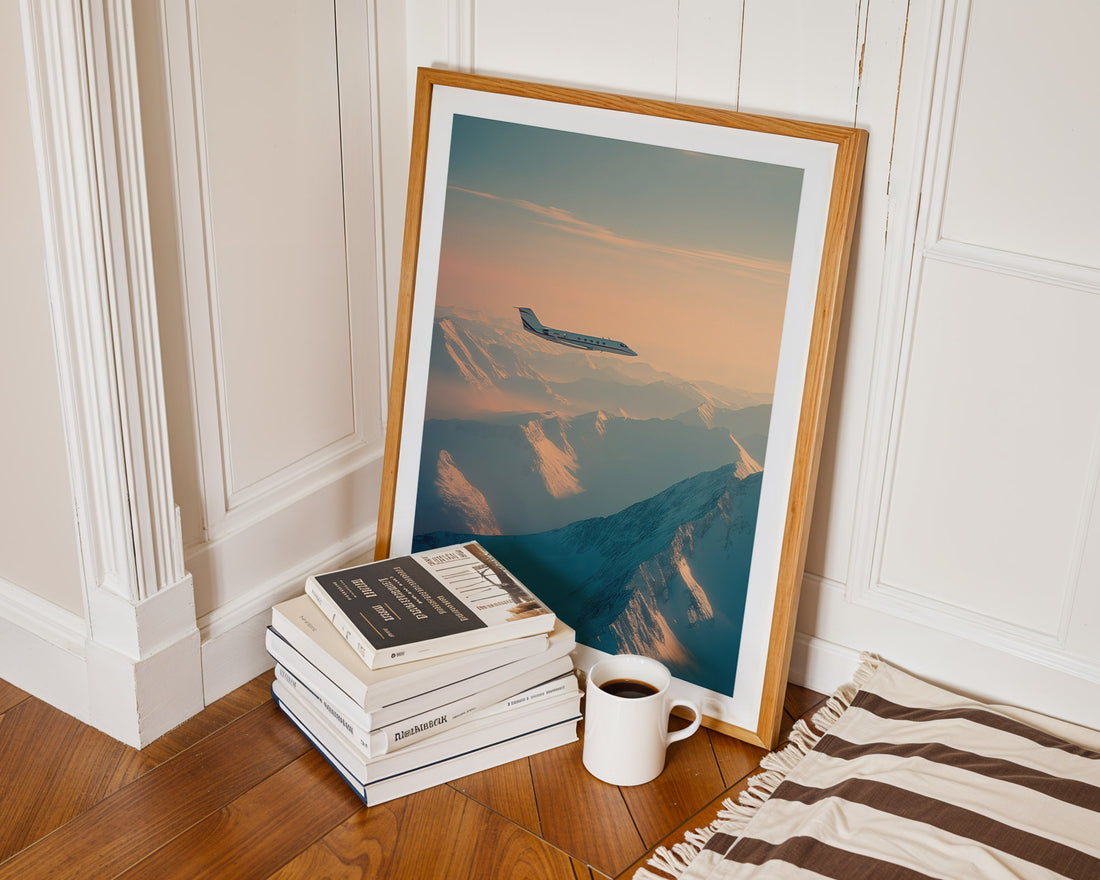 Framed artwork of an airplane in the sky on a wooden floor with books and a mug.