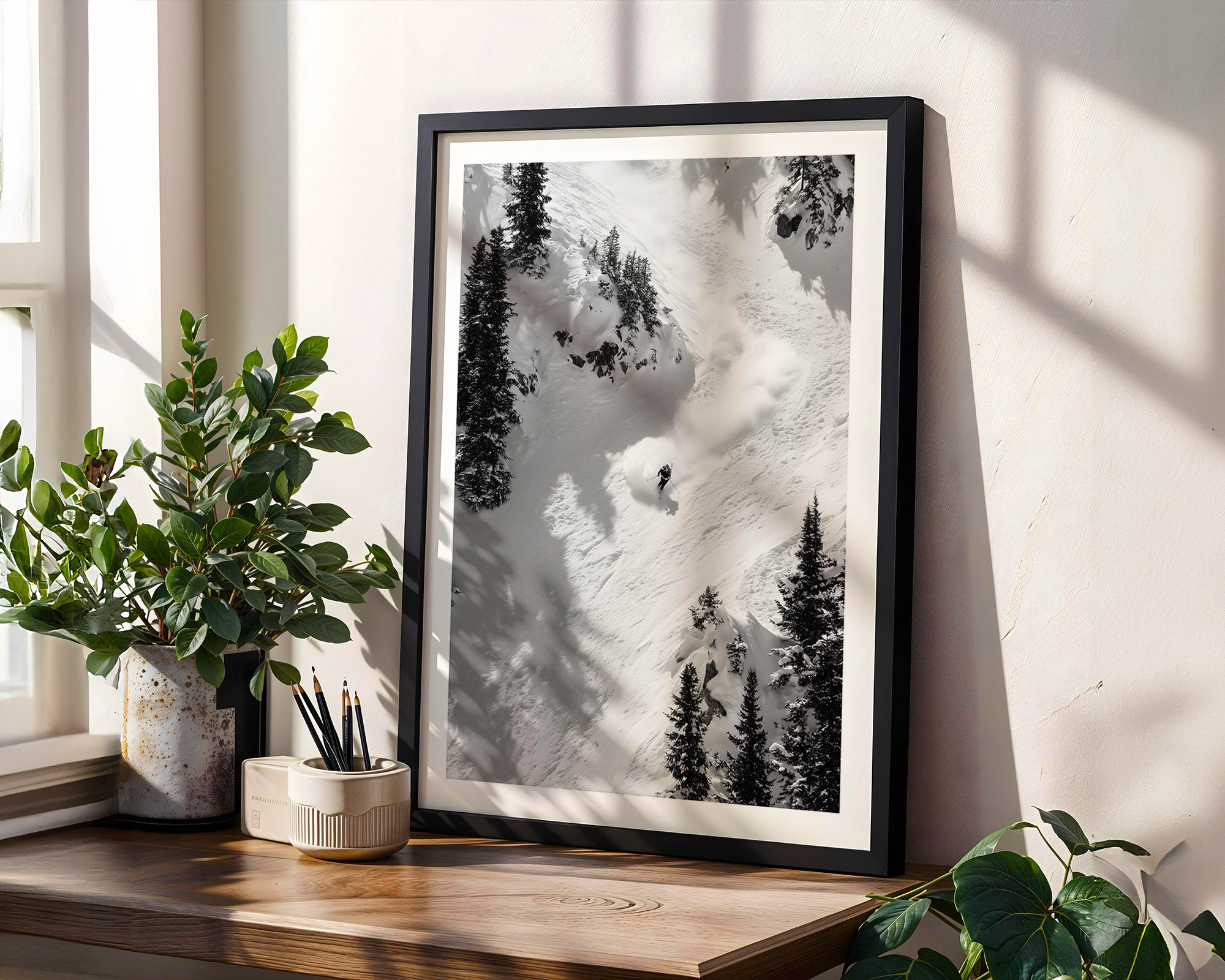 Framed black and white nature print on a wooden shelf with plants