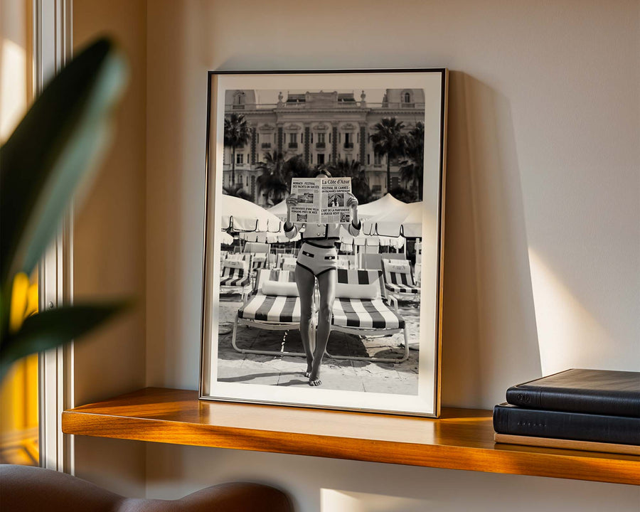 Framed black and white photograph of a person on a beach with lounge chairs.