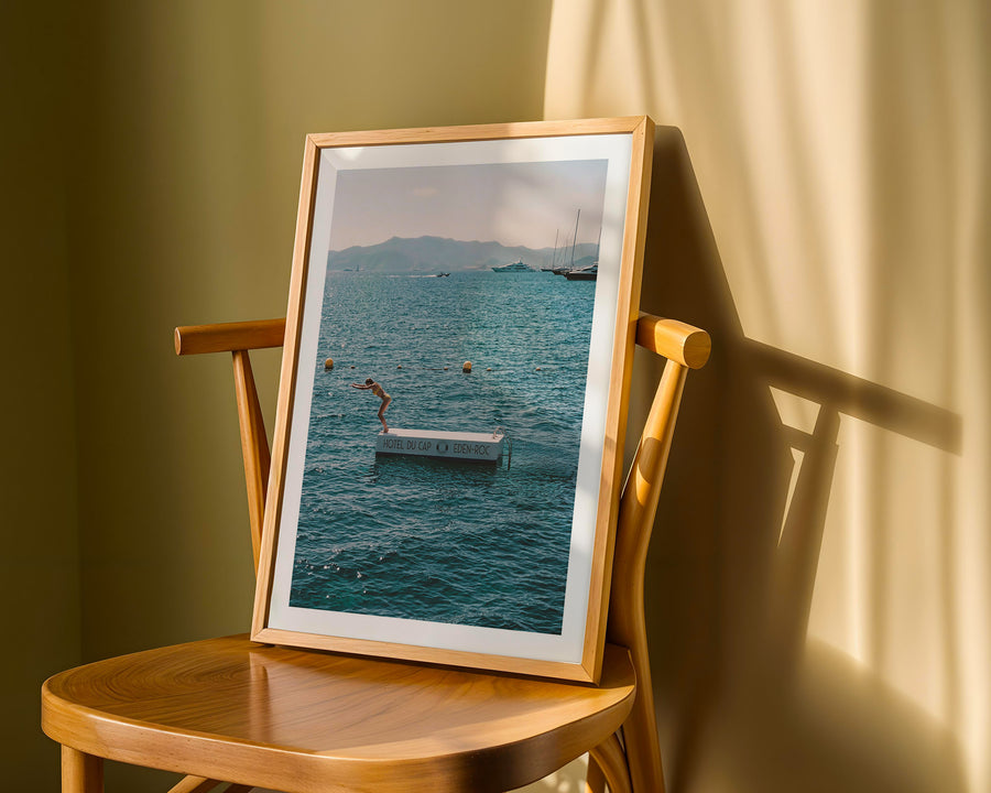 Framed photograph of a beach scene on a wooden chair with a soft light background
