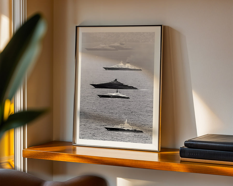 Framed artwork of boats on water displayed on a shelf.