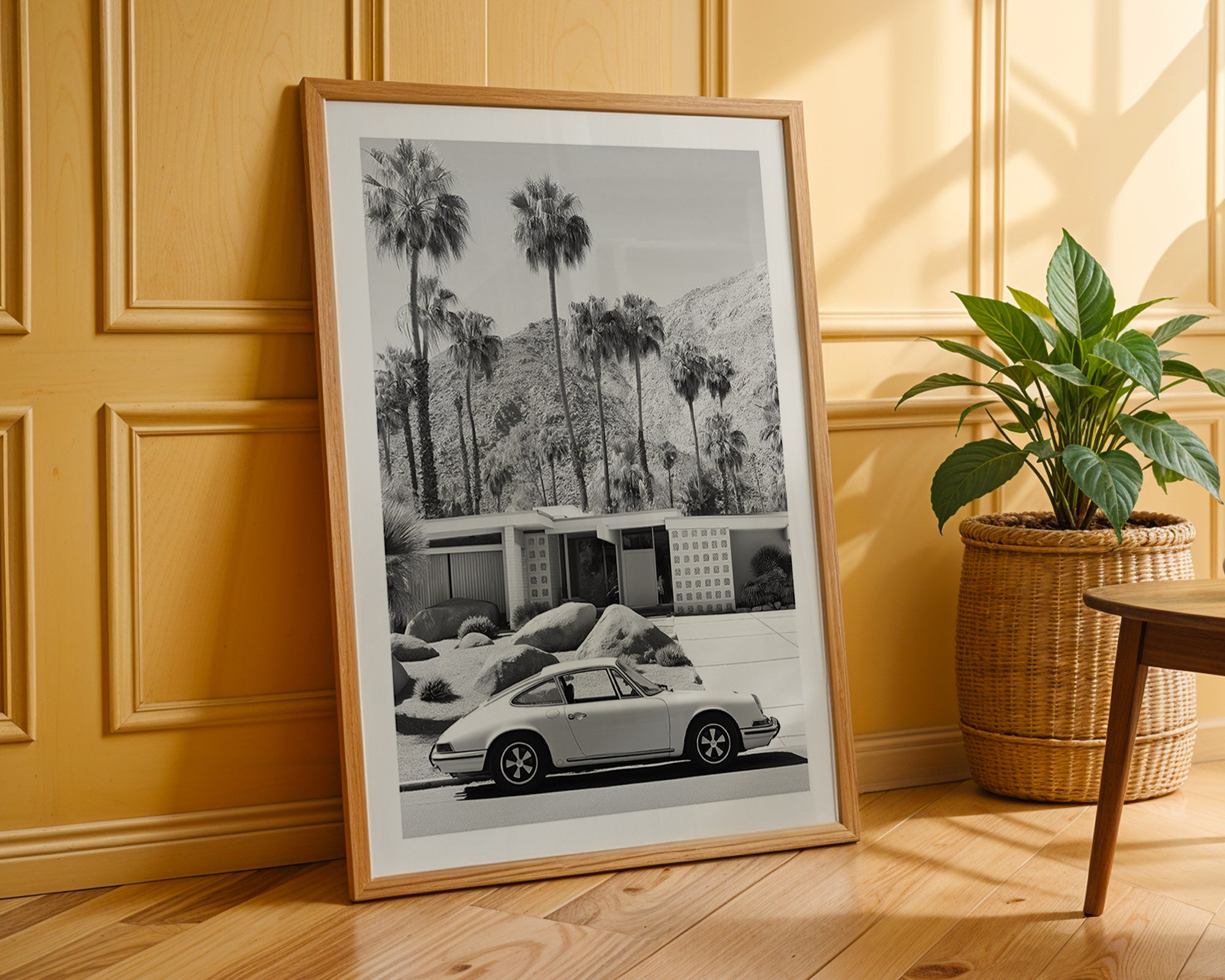 Framed black and white print of a car and palm trees leaning against a wooden wall.