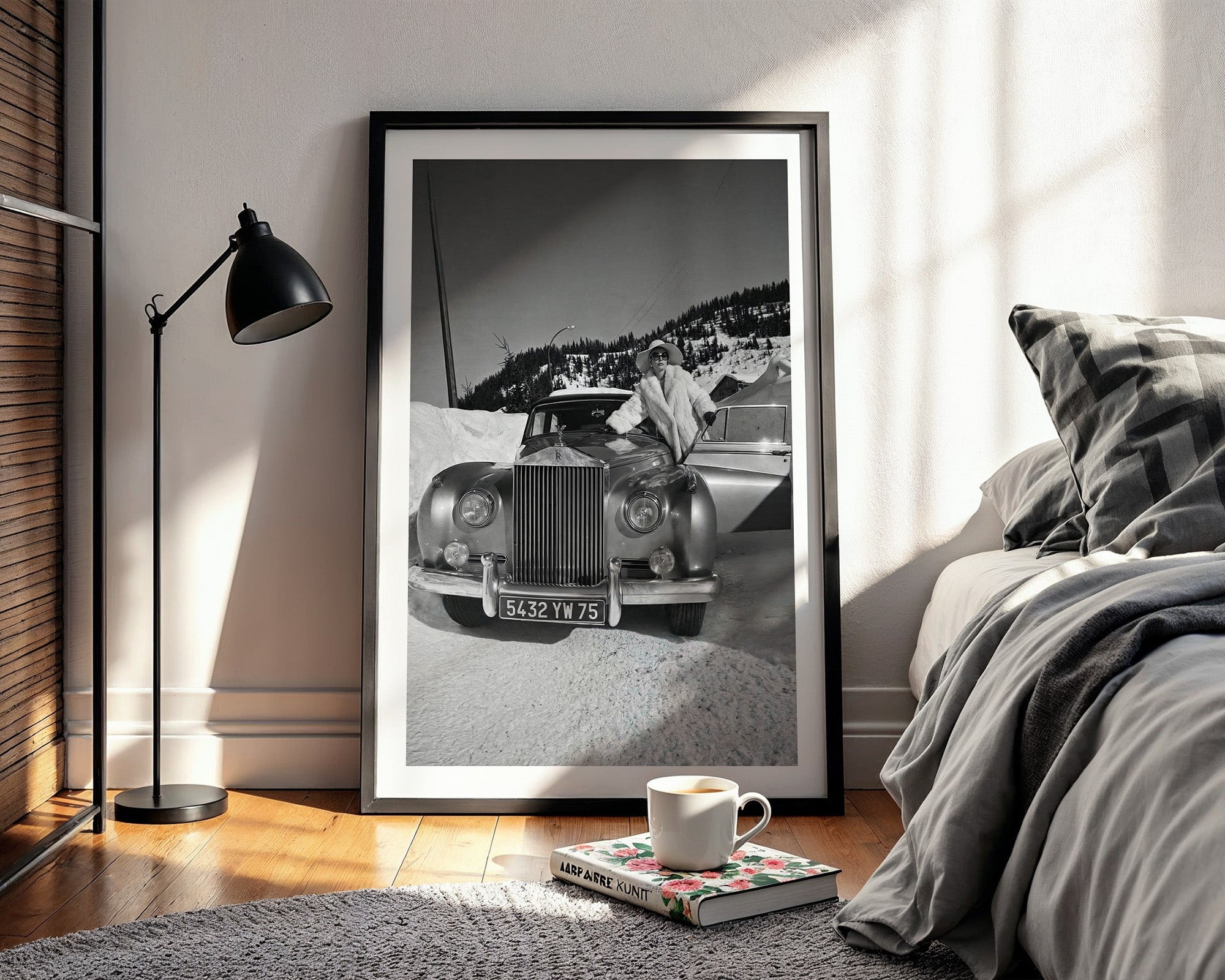 Framed black and white photograph of a vintage Rolls-Royce in a bedroom setting with a lamp and bed.