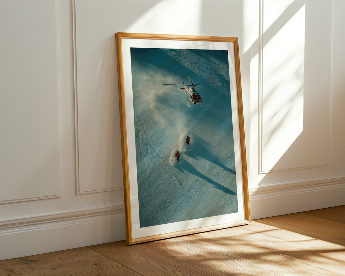 Framed artwork of a helicopter and 2 persons skiing in the alps.