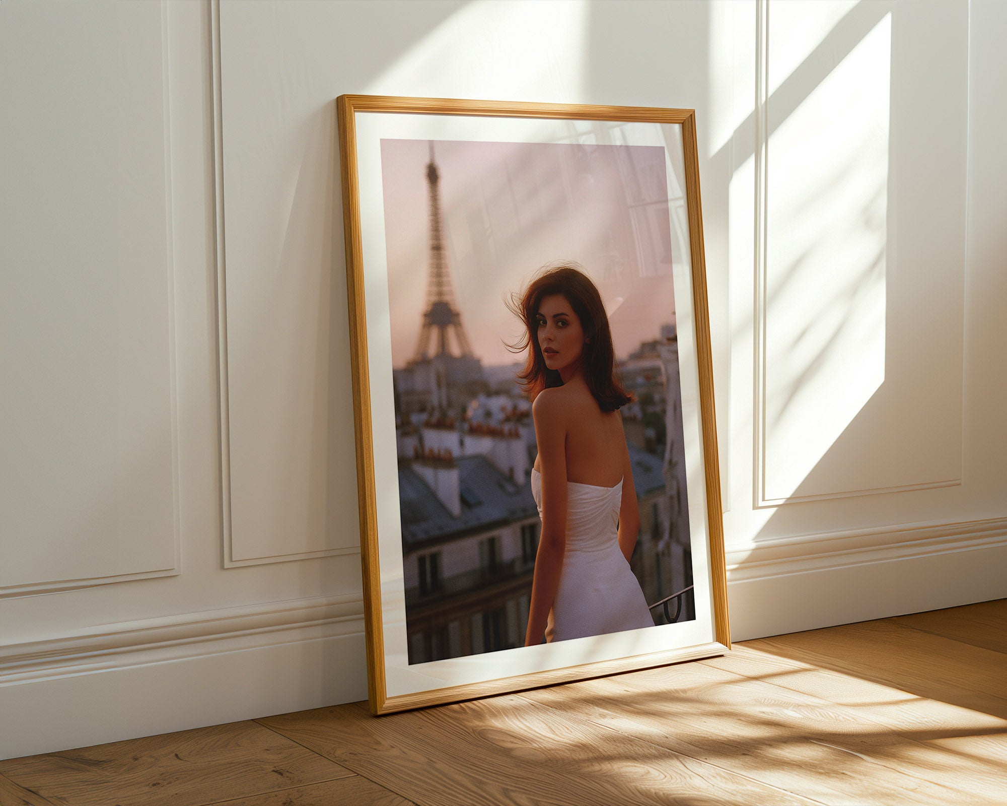 Framed photograph of a woman in a white dress with the Eiffel Tower in the background, leaning against a wall.