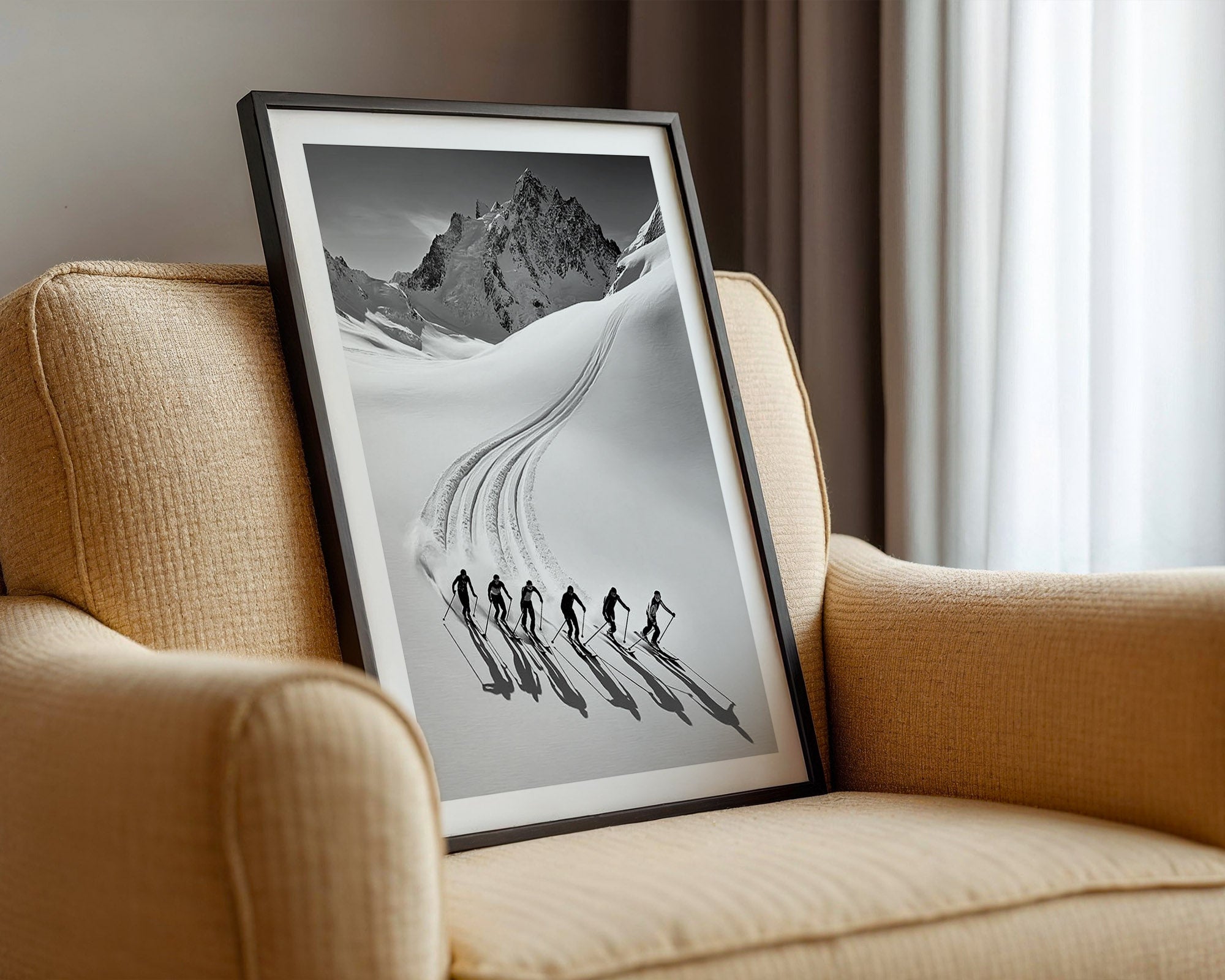 Framed black and white artwork of skiers on a mountain slope displayed on a beige sofa.