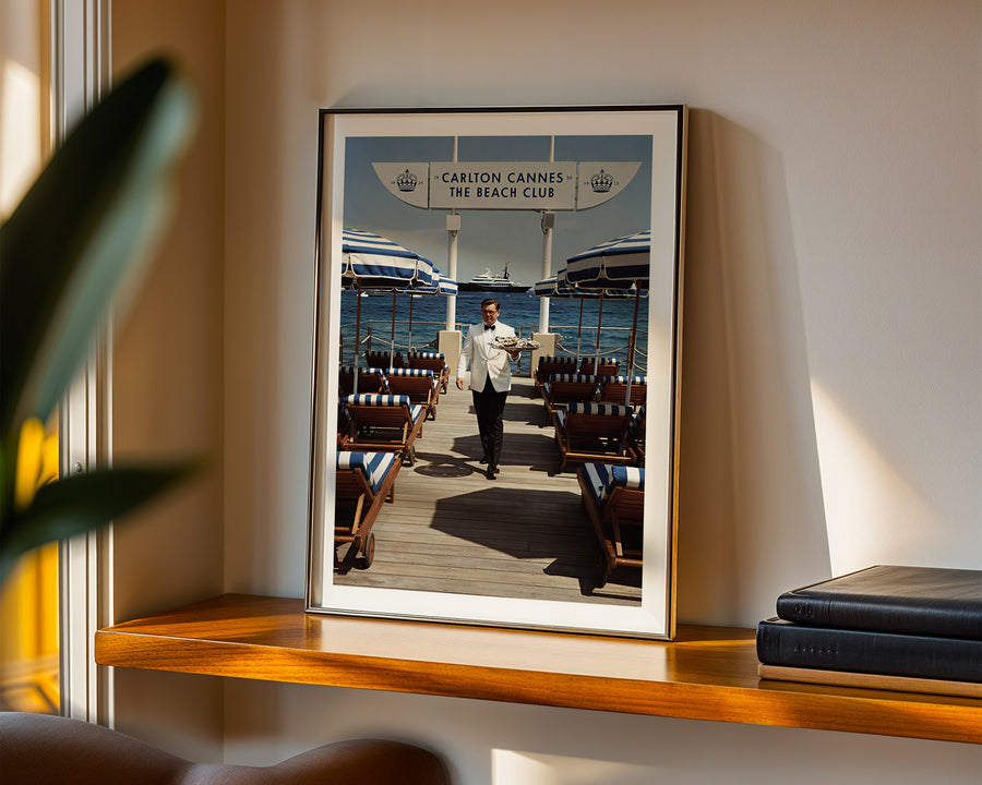 Framed photograph of a man on a dock with boats in the background, displayed on a wooden shelf.