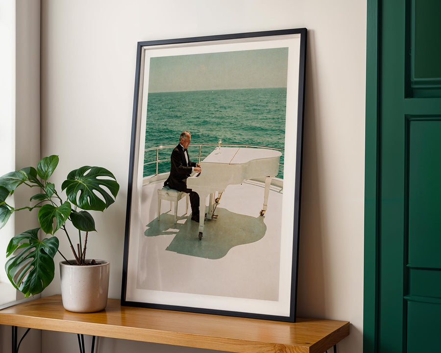 Framed photograph of a person on a boat next to a plant on a wooden table.