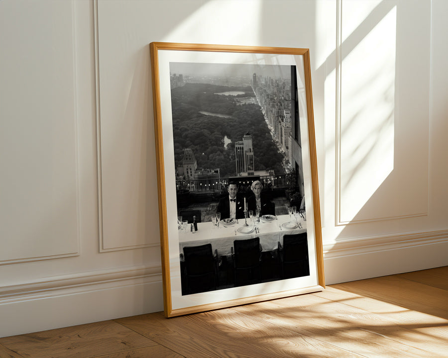 Framed black and white cityscape print on a wall with sunlight casting shadows.