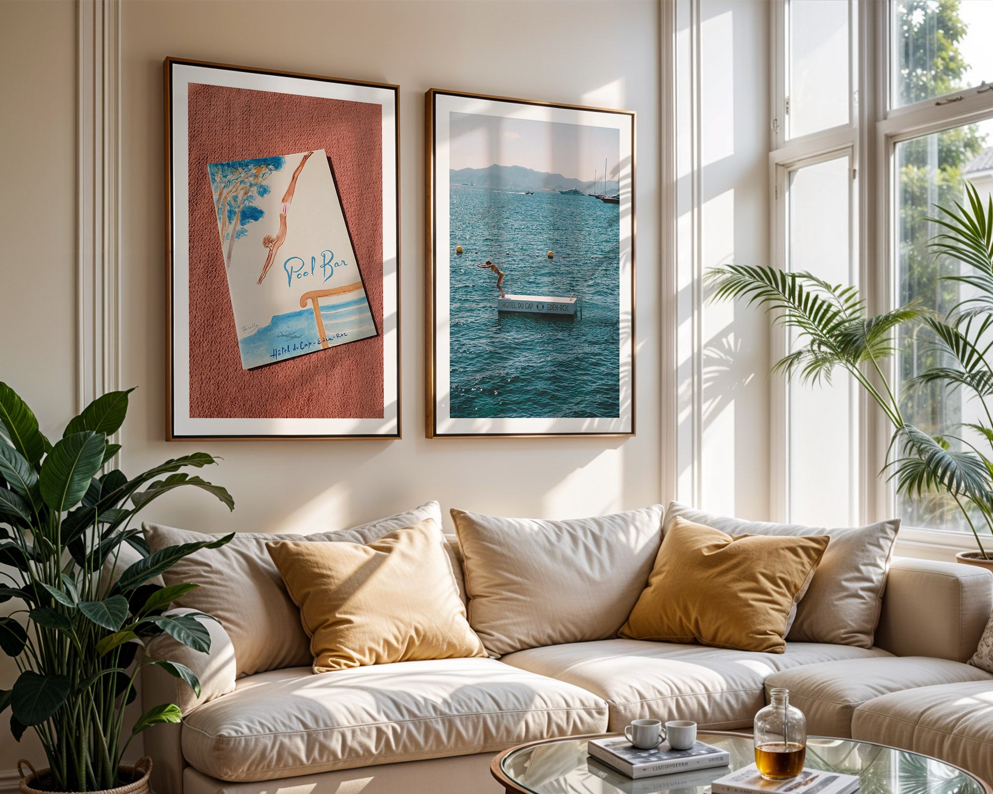 Living room with a beige sofa, framed artwork with Hôtel du Cap-Eden-Roc, and plants.