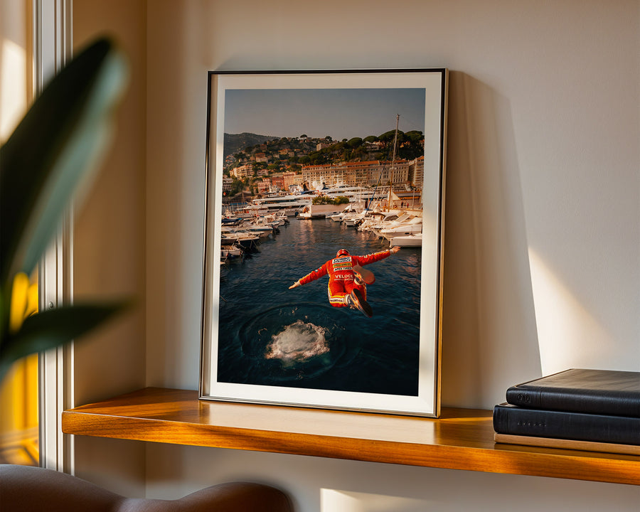 Framed photograph of a person in a red jacket standing on water with a scenic background, displayed on a wooden shelf.