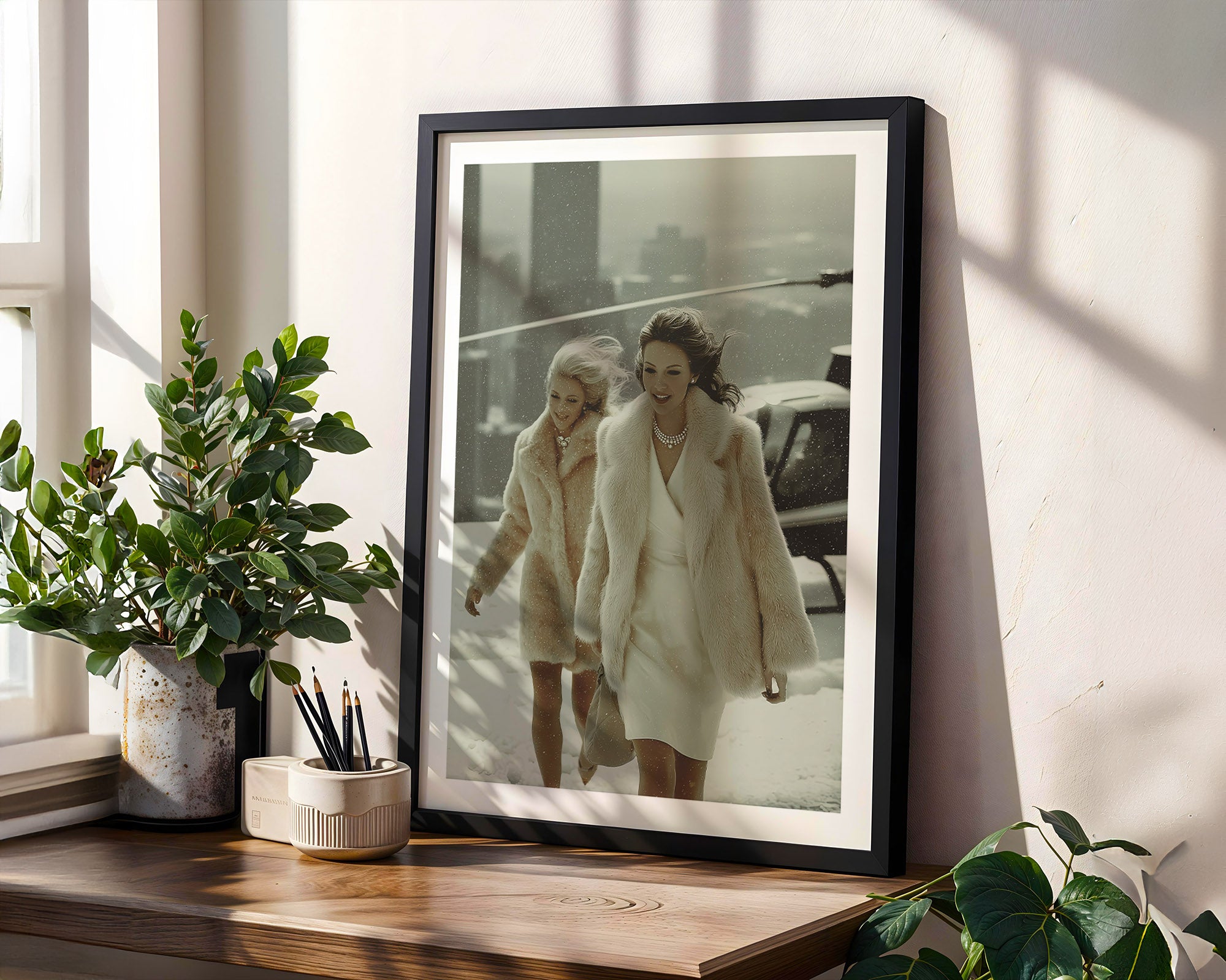 Framed photograph of two woman walking from a helicopter, placed on a wooden surface with plants around.