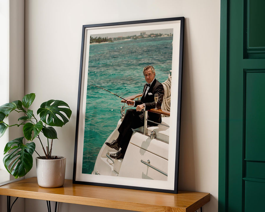 Framed photograph of a man on a boat with a scenic background, displayed on a wooden shelf.