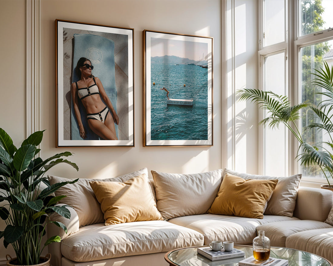 Living room with a beige sofa, decorative pillows, and framed posters of a woman in a bikini and a person diving in the water at Hotel du Cap-Eden-Roc.