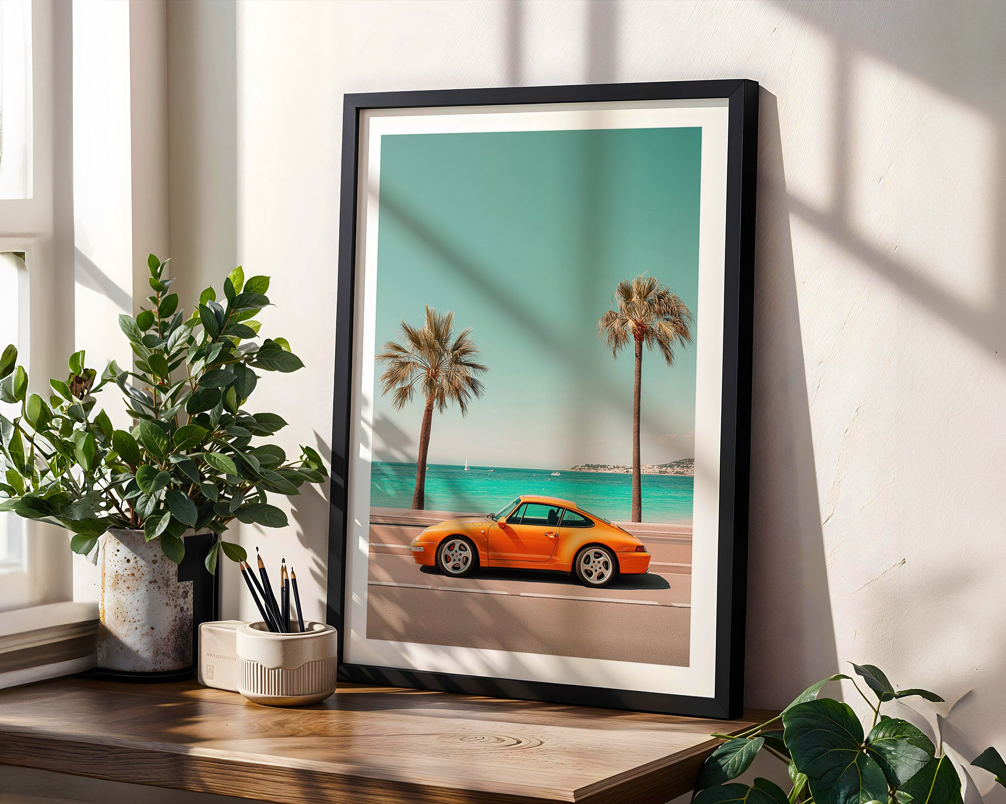 Framed artwork of an orange Porsche on a beach with palm trees and blue sky.