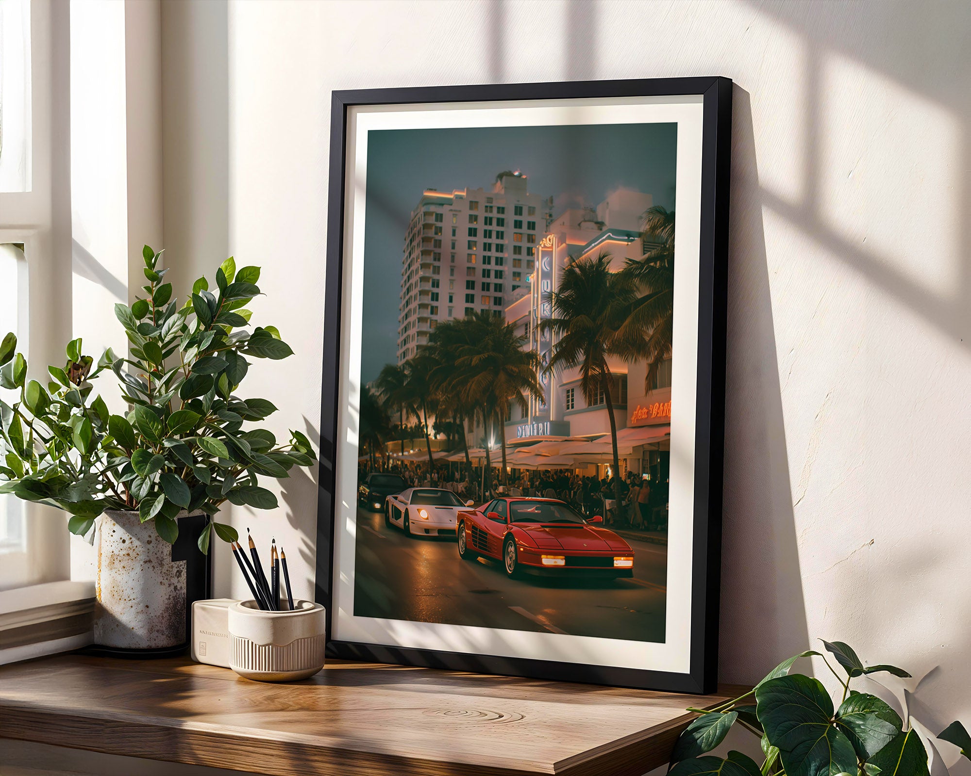 Framed artwork of a city street scene in Miami with palm trees and cars on a wooden shelf.