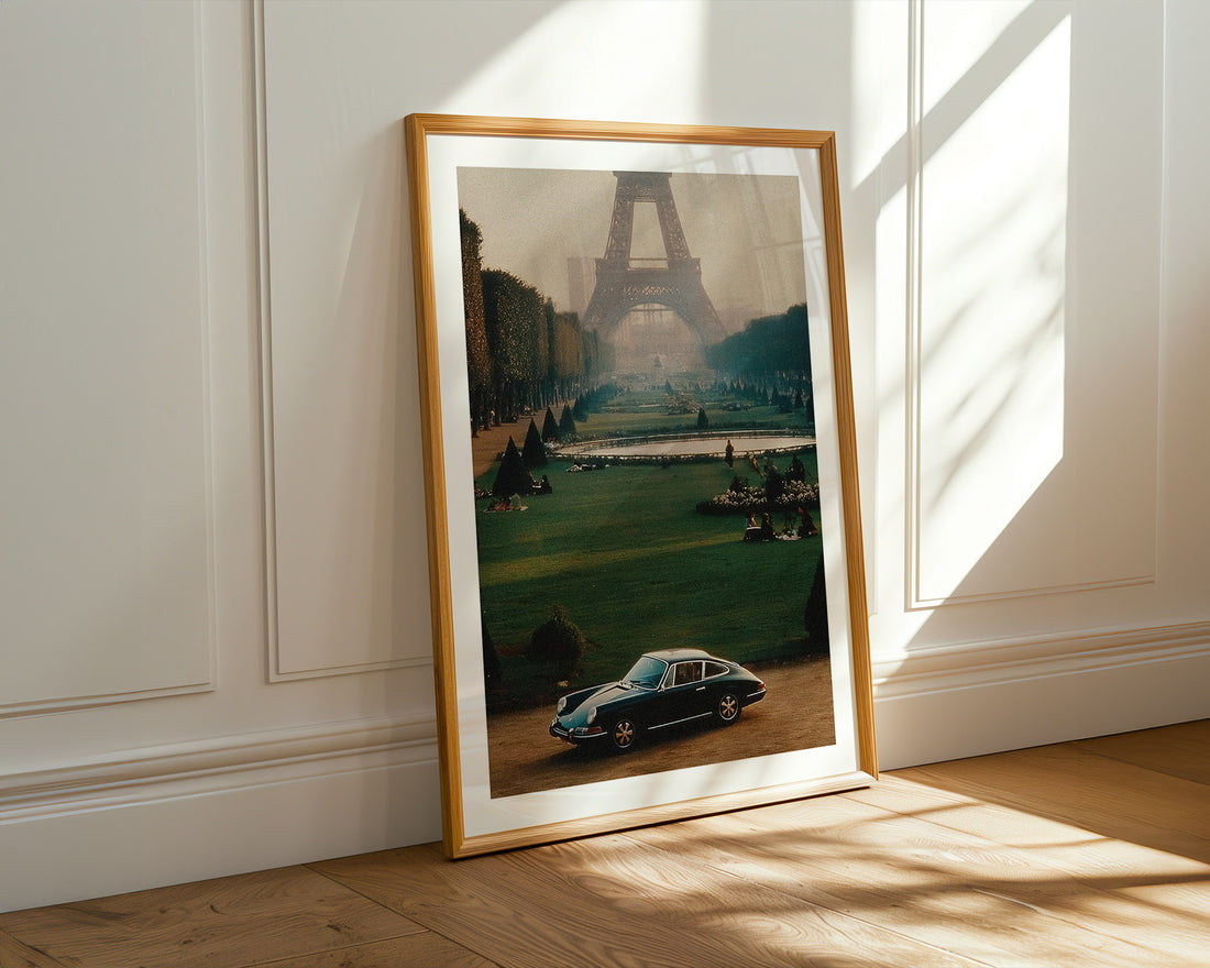 Framed photograph of a car in front of the Eiffel Tower on a wall with sunlight filtering through.