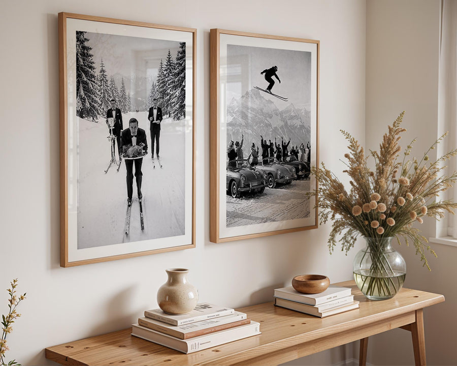Two framed black and white photos on a wall above a wooden console table with decorative items.