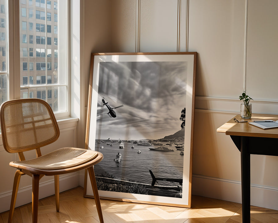 Framed black and white artwork on a wall next to a chair and table.