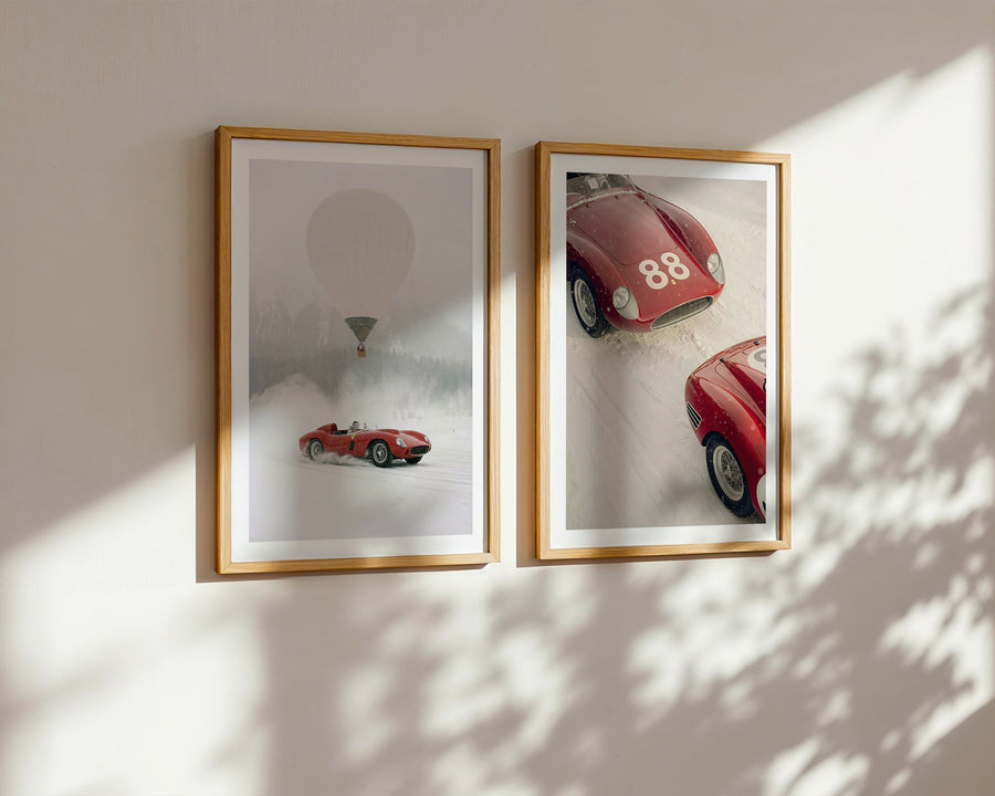 Two framed pictures of red cars on a wall with soft shadows.