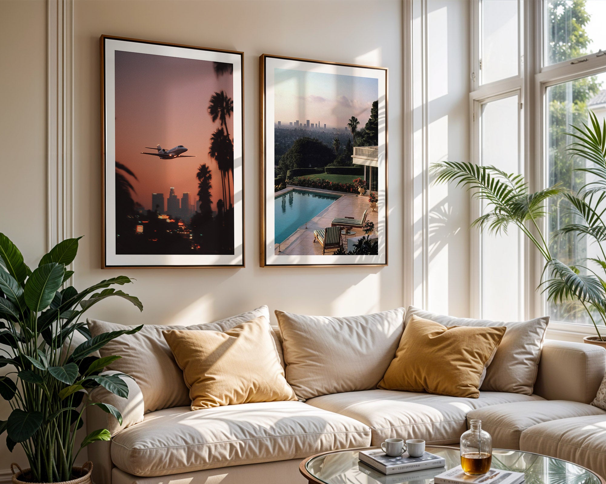 Living room with a beige sofa, framed artworks of Los Angeles , and a view of a pool and cityscape.
