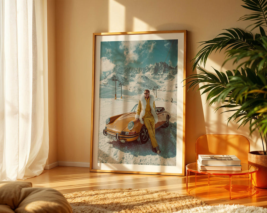 Framed artwork of a person with a vintage car in a snowy landscape, placed in a room with a plant and table.