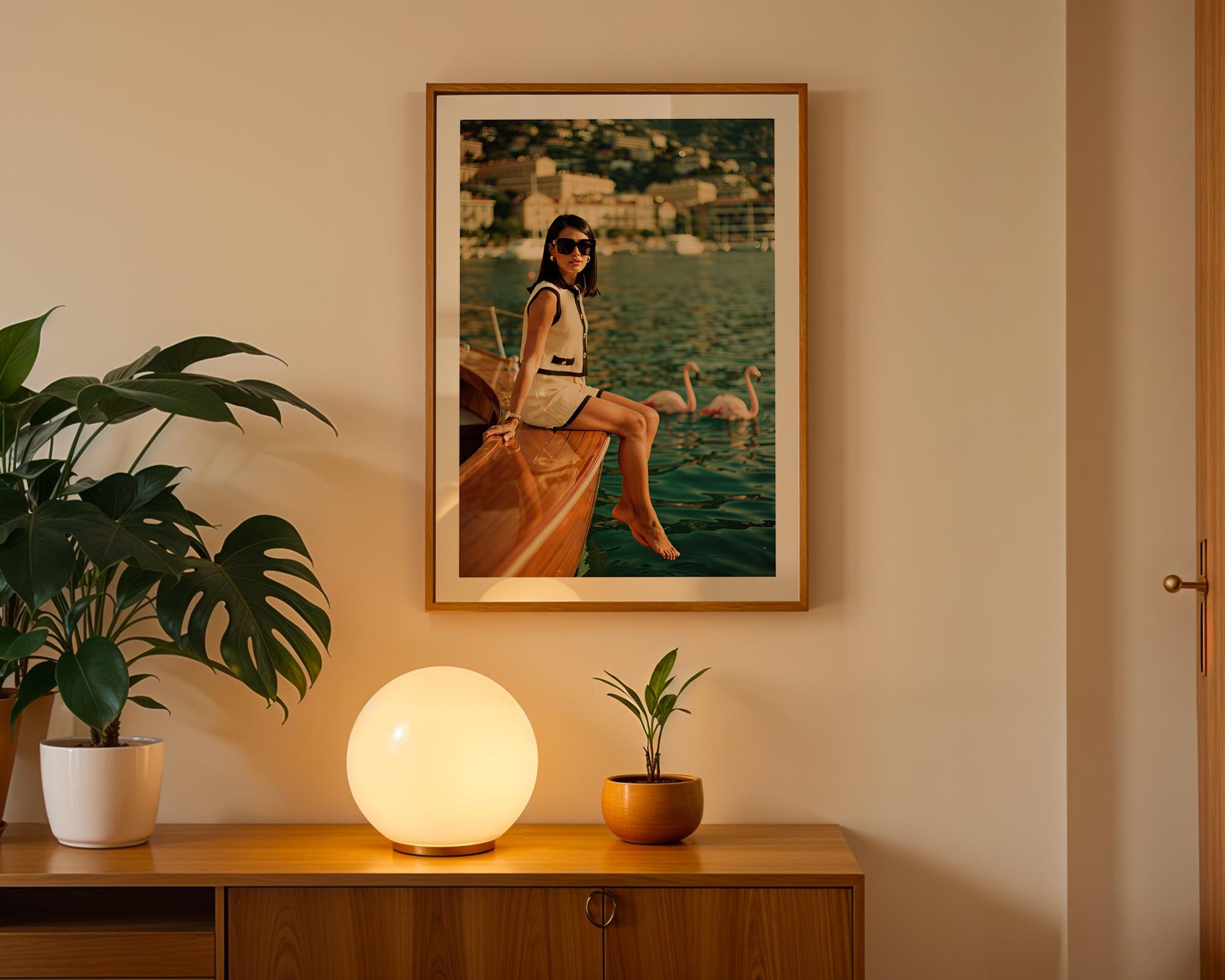 Framed artwork of a woman on a boat with swans, placed above a wooden cabinet with decorative items.
