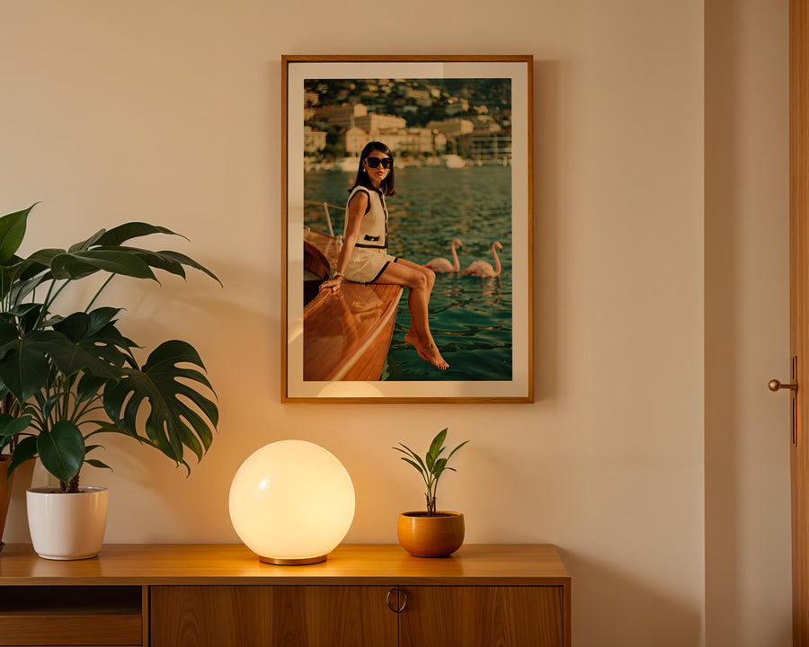 Framed artwork of a woman on a boat with swans, placed above a wooden cabinet with decorative items.