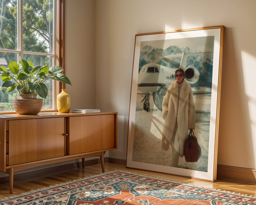 Framed artwork of a woman in a fur coat leaning against a wall in a room with a wooden sideboard and decorative rug.