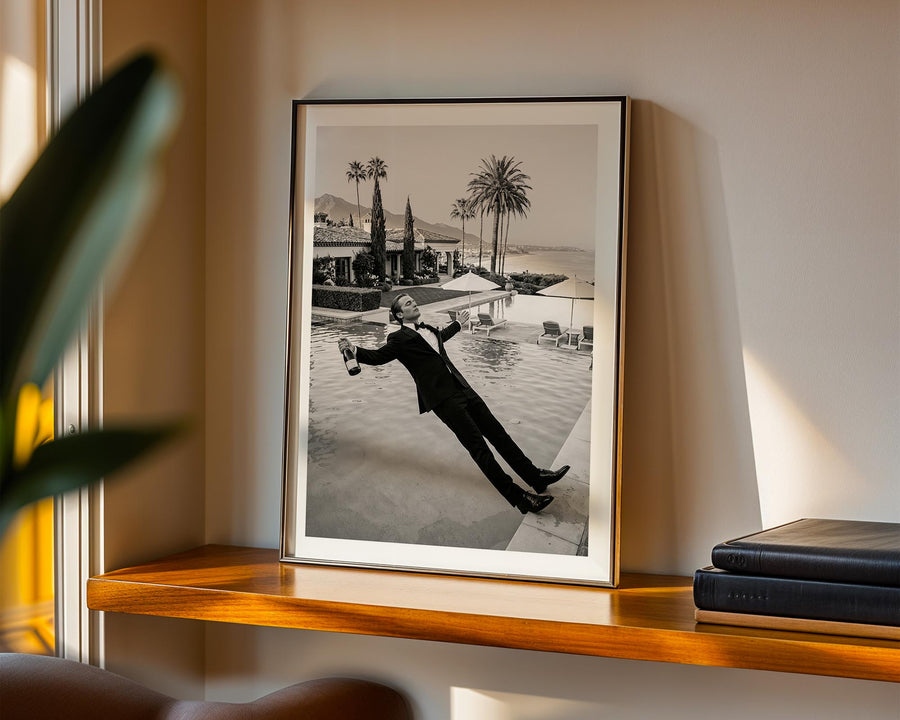 Framed black and white photograph of a man by a pool on a wooden shelf.