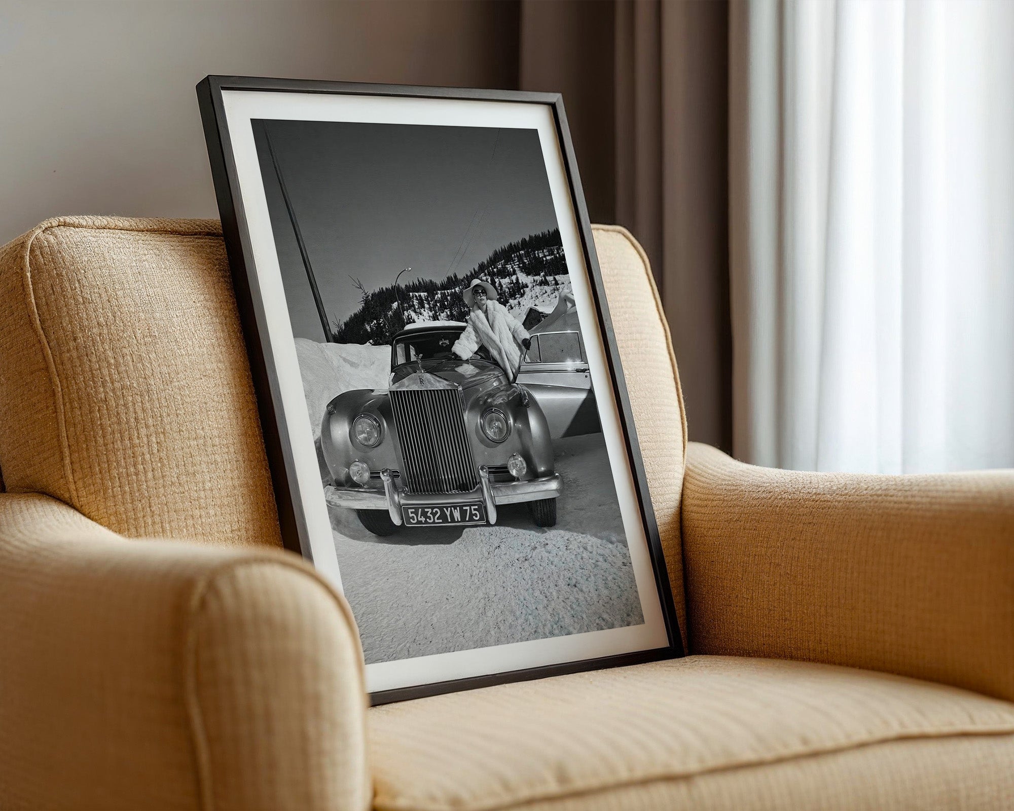 Framed black and white photograph of a vintage Rolls-Royce car on a beige armchair.