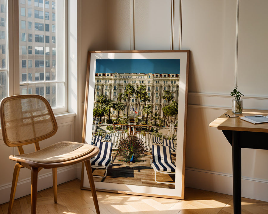 Framed photograph of a cityscape leaning against a wall in a room with a chair and table.