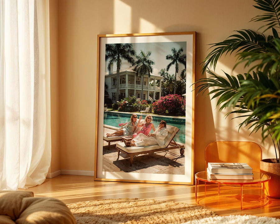 Framed photograph of a family by a pool in a living room with a plant and table.