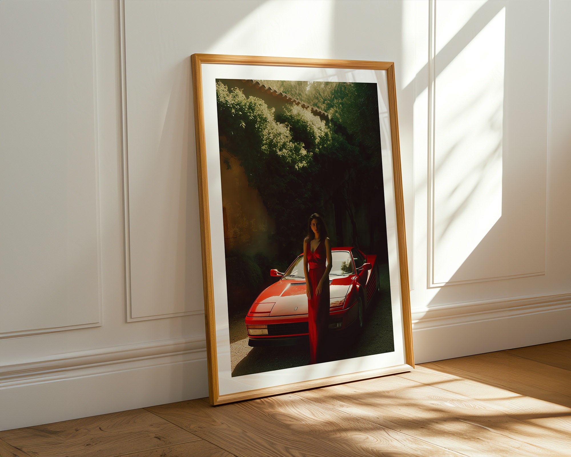 Framed photograph of a red car and person on a wooden floor with sunlight filtering through.
