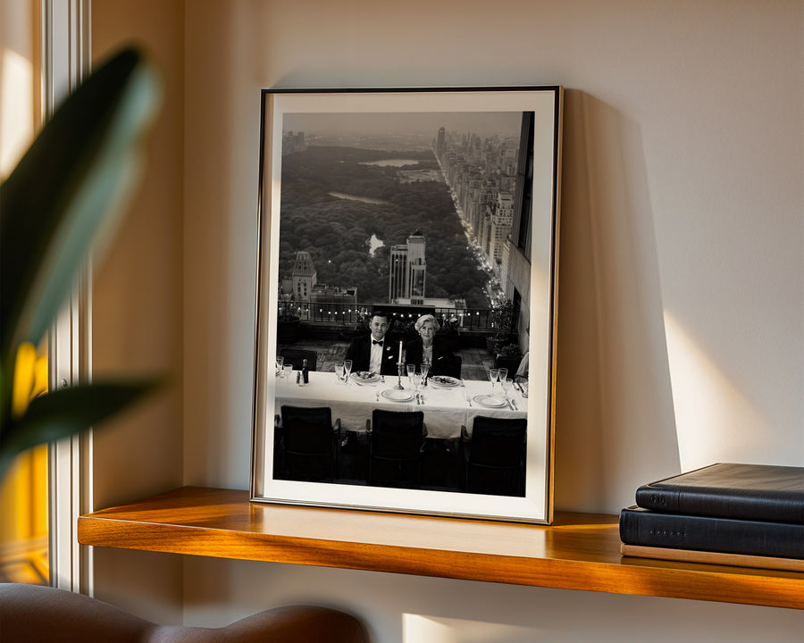 Framed black and white photograph of a cityscape with people at a table on a wooden shelf.