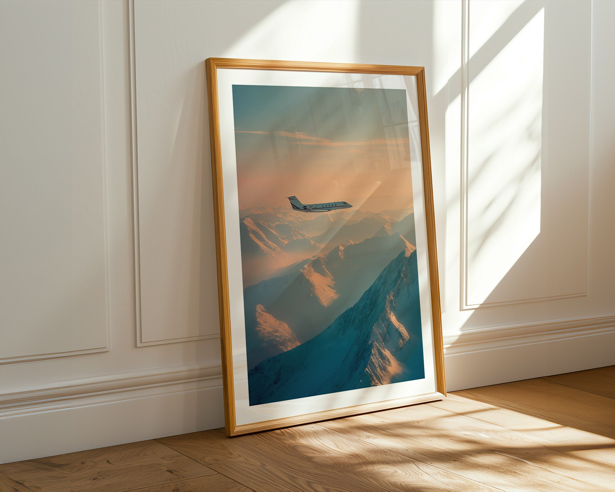 Framed artwork of an airplane flying over a mountain range in a sunlit room.