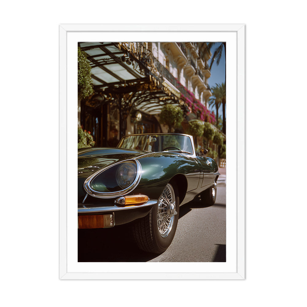 Vintage green car parked on a street with palm trees and a building in the background
